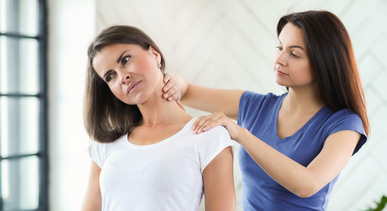 Therapist applying pressure to a patient's neck and shoulder area to relieve trigger points in a bright, modern setting
