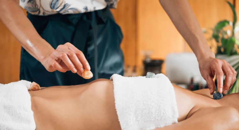 A practitioner performing a healing therapy using crystals placed on a person's abdomen, possibly for energy balancing, chakra healing, or alternative wellness treatment.
