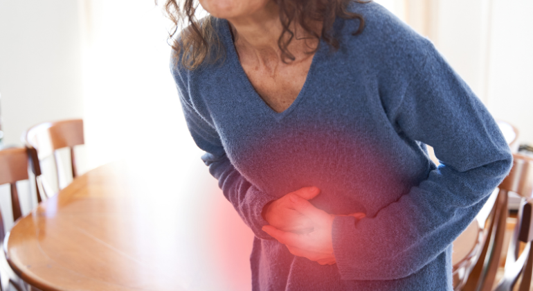 A woman clutching her lower abdomen in pain, indicating discomfort possibly caused by navel displacement or digestive issues.